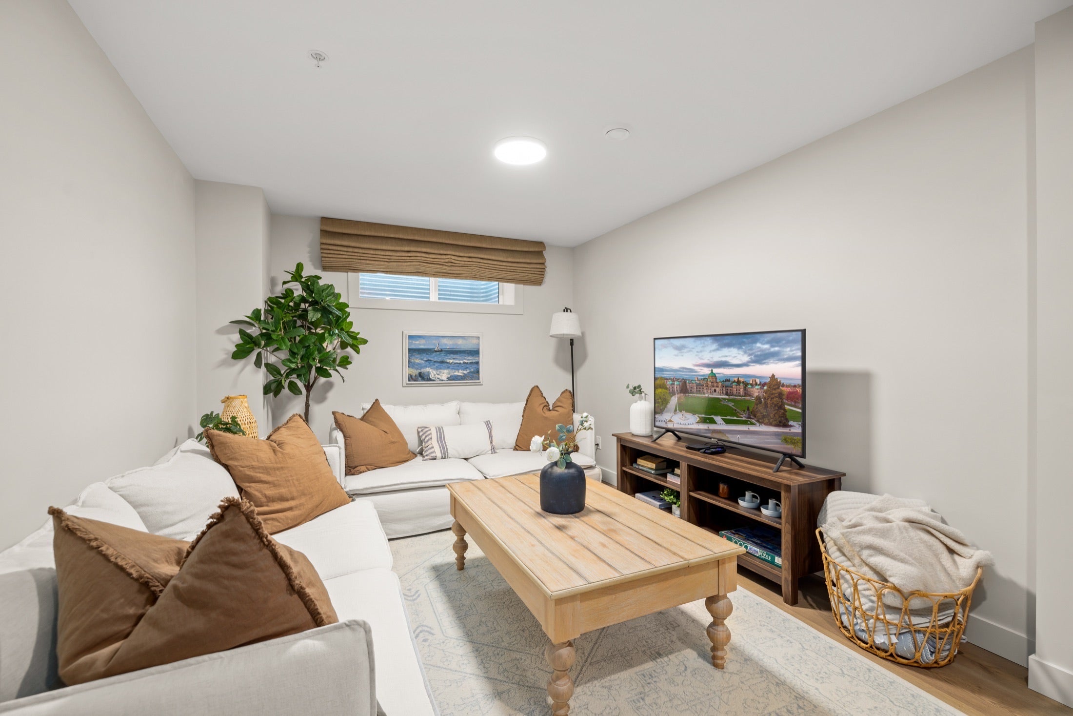 Bright furnished living room with sofas, coffee table and television